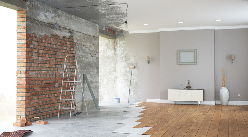 Een kamer ondergaat een stijlvolle renovatie, waarbij moderne trends zoals houten vloeren en een bakstenen muur zijn verwerkt.