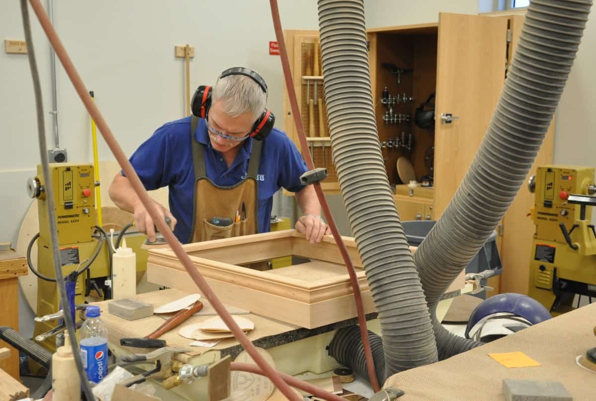 In een werkplaats van Schrijnwerken werkt een man aan een stuk hout.