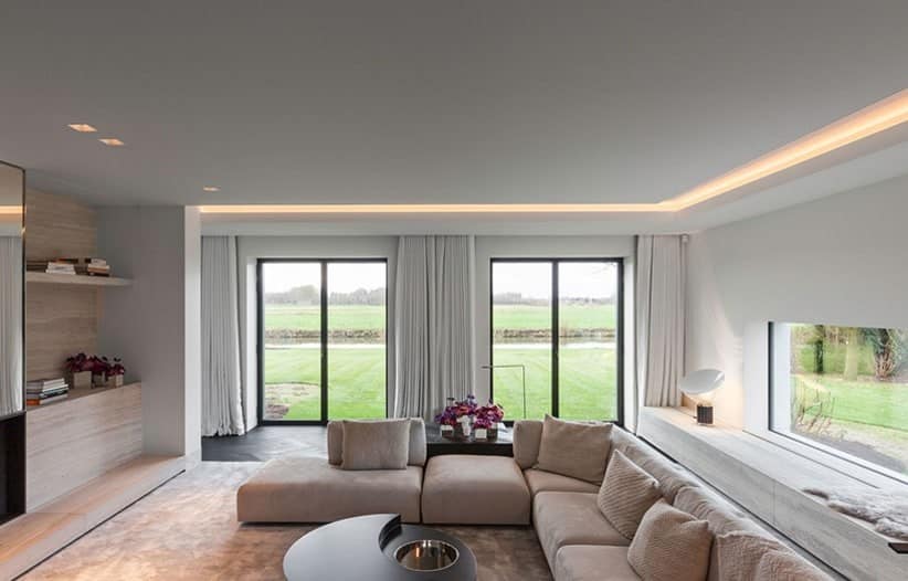 Een moderne woonkamer met open haard en grote ramen ontworpen met interieurbouwtechnieken.